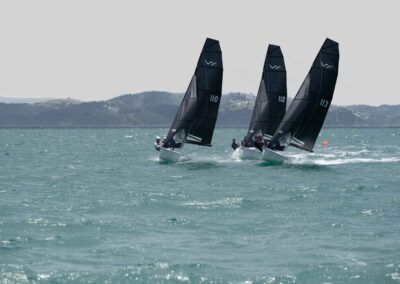 Three sailboats racing on choppy sea waters