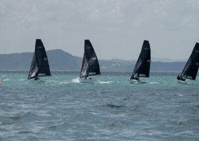 Four sailboats racing on the ocean near coastline