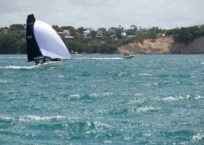 Sailboats racing on choppy coastal waters near cliffs