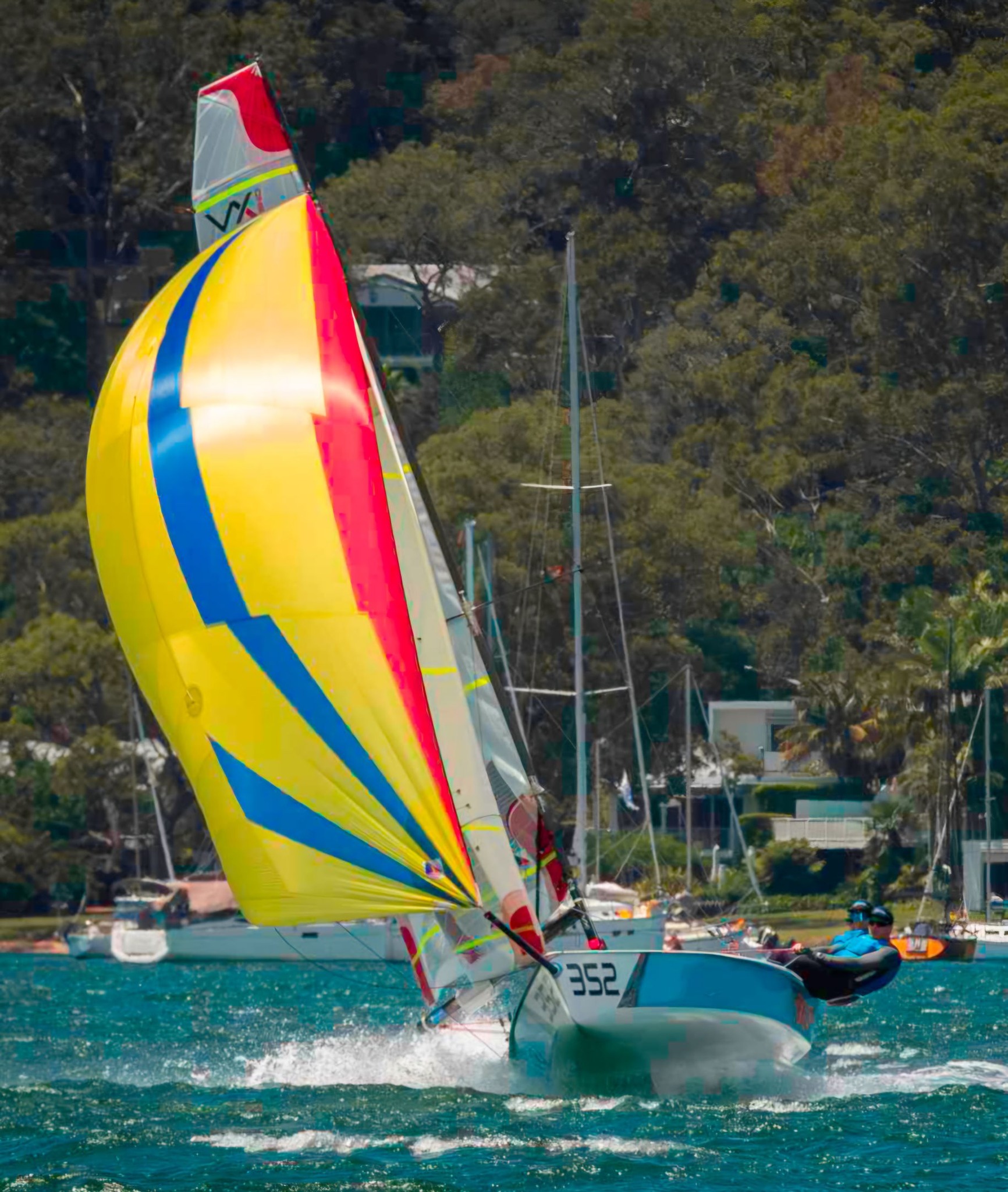 Sailboat racing with colourful spinnaker on sunny day