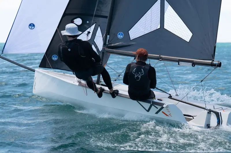 Two sailors racing a small yacht on ocean waves