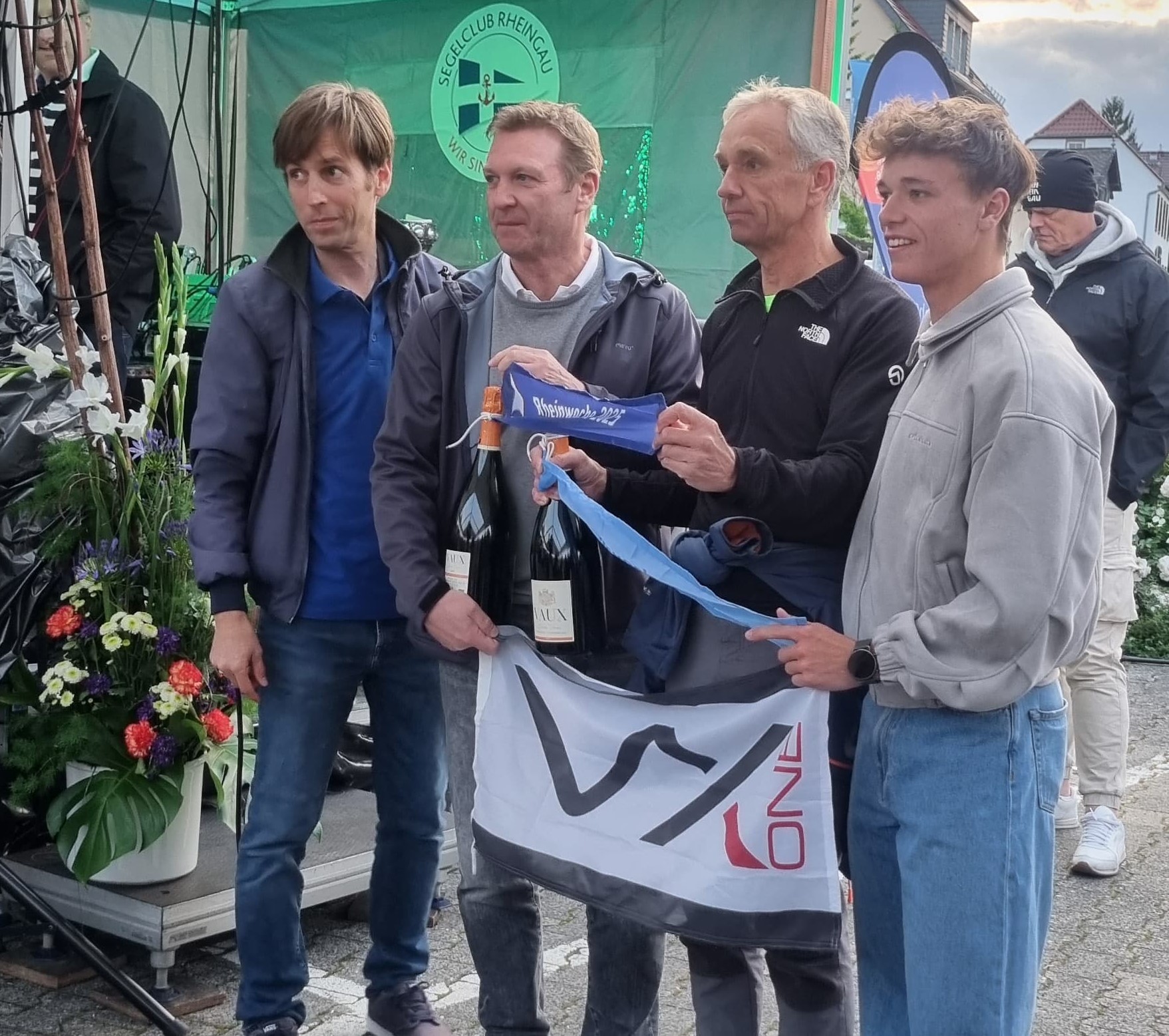 Team celebrating with wine bottles and flag at event