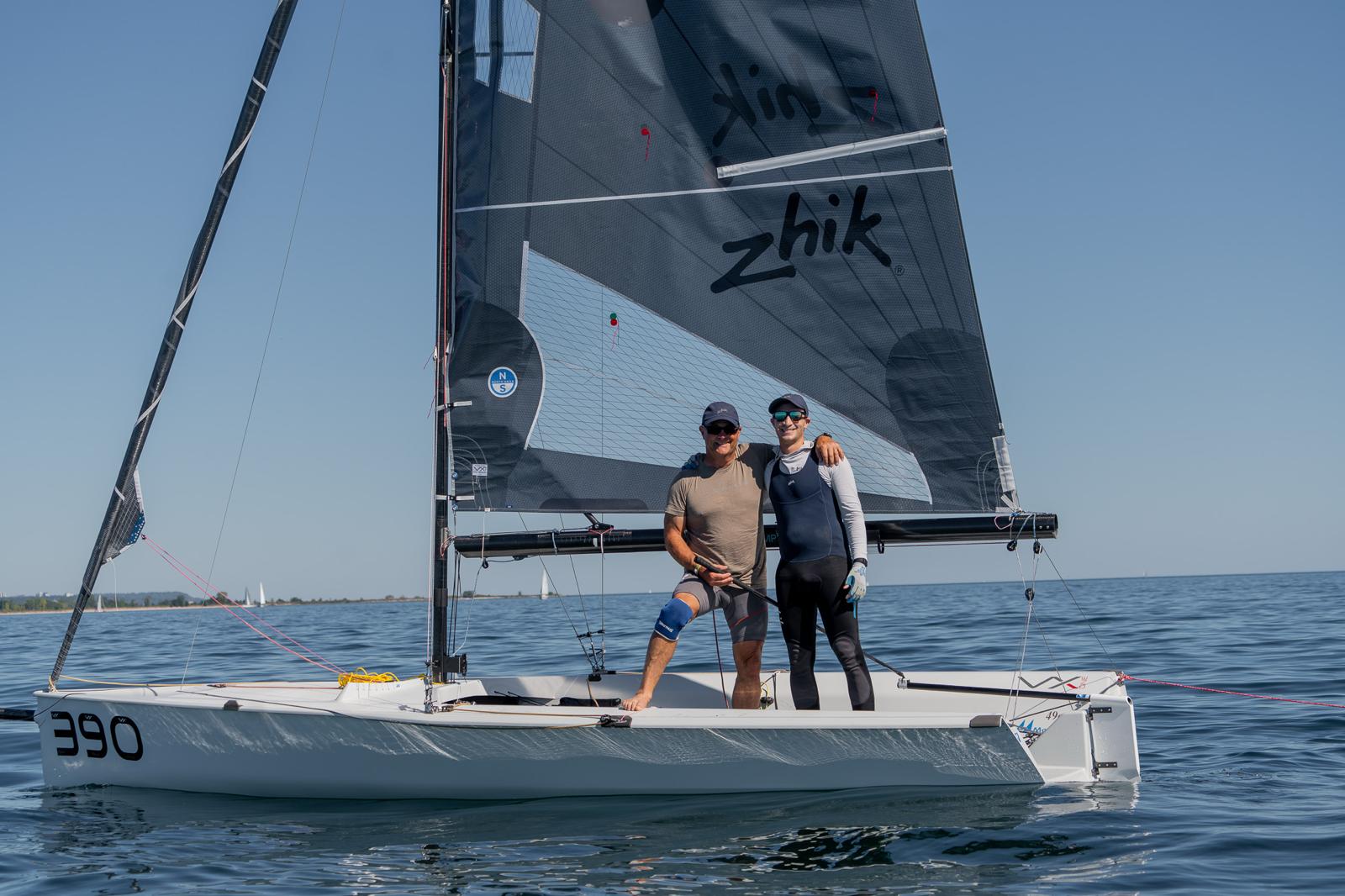 Two sailors standing on a small sailboat